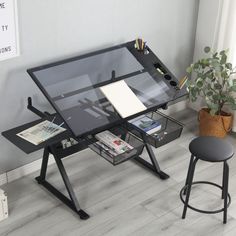 an office desk with a glass top and black metal frame, on the floor next to a potted plant