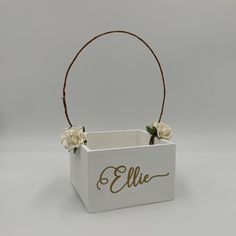 a white box with flowers in it and the name ellie written on the front side