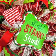 a green and red christmas wreath with the words stink on it