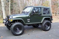 a green jeep is parked in front of some trees