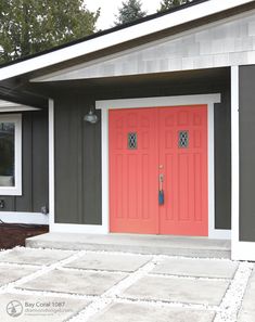 a red door sits in front of a gray house