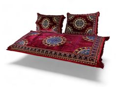 a red bed with two pillows and some decorative designs on it's coverlet