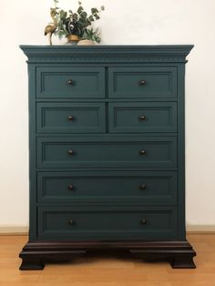 a green dresser sitting on top of a hard wood floor next to a white wall