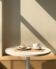 a white table topped with a plate of food and a cup of coffee next to it