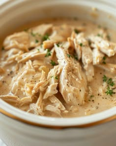 a bowl filled with chicken and gravy on top of a white table cloth