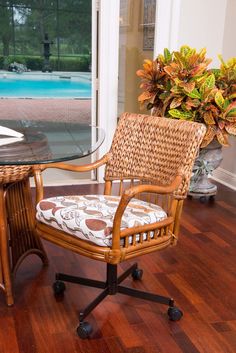 a wicker desk chair sitting next to a glass table with a flower pot on it