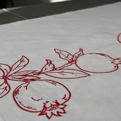 an embroidered tablecloth with fruit and leaves on it