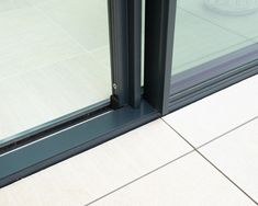 an open sliding glass door on the outside of a building with white tile flooring