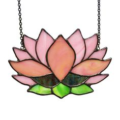 a pink and green stained glass flower hanging from a metal chain on a white background