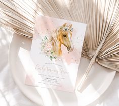 a card with a horse on it next to a fan and palm leaf decoration in the background