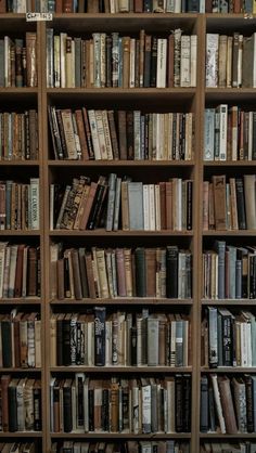 a bookshelf filled with lots of books on top of wooden shelves in a room