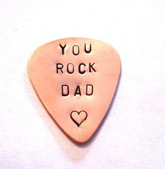 a pink guitar pick with the words you rock dad written on it's side