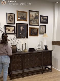 a woman is looking at pictures on the wall