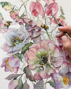 a woman's hand holding a paintbrush and drawing flowers