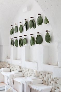 a room with white furniture and green leaves hanging on the wall above it's windows