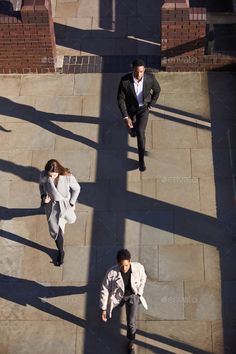 two people walking down a sidewalk in the sun