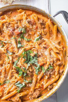 a large pot filled with pasta and meat sauce on top of a white tablecloth