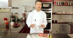 a man in a chef's outfit standing next to a cutting board with meat on it