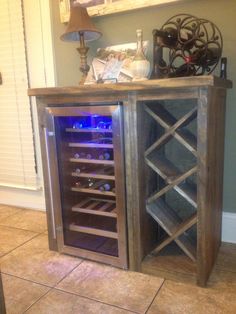 a wooden cabinet with wine bottles in it and a lamp next to it on the floor