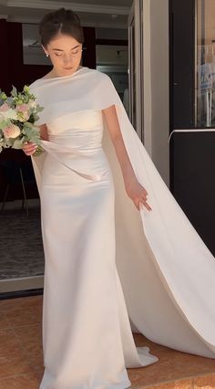 a woman in a white wedding dress holding a bouquet