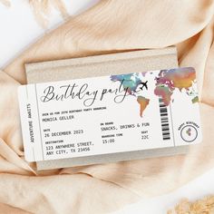 a birthday party ticket sitting on top of a beige blanket next to a stuffed animal