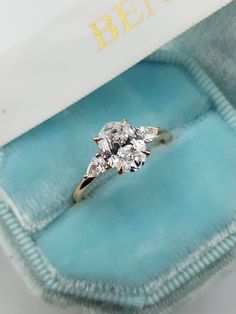 an engagement ring with three stone diamonds in a blue velvet box on top of it