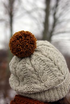 a person wearing a hat with a brown pom - pom on the top