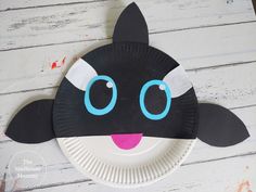 a paper plate with a black cat face on it's side and blue eyes