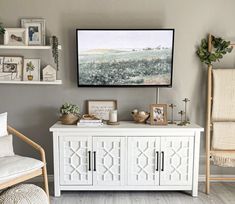 a living room with white furniture and pictures on the wall