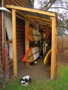 there are many surfboards in the shed and one dog is laying on the ground