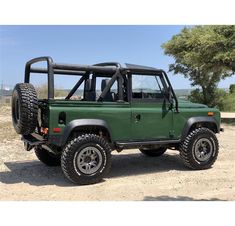 a green jeep parked on top of a dirt field