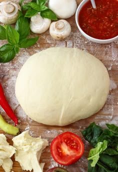 ingredients for pizza laid out on a cutting board including tomatoes, basil, garlic, and bread