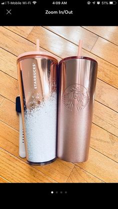 two starbucks tumblers sitting on top of a wooden floor