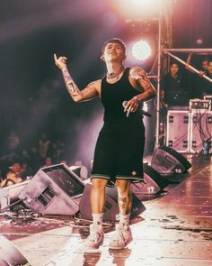 a woman standing on top of a stage with her arms out in front of the crowd