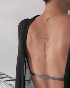 the back of a woman's body with a flower tattoo on her left side