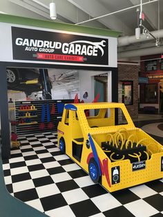 a yellow truck with tools in the bed is on display at an auto repair shop