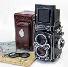 an old fashioned camera sitting on top of a table next to a card and sunglasses