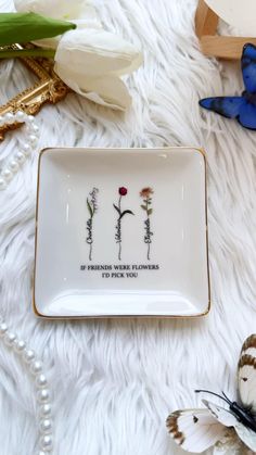 a plate with flowers on it sitting on a white furnishing next to butterflies