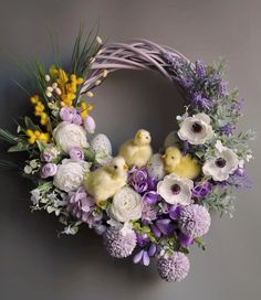 a wreath with white and purple flowers, yellow chicks and greenery on the front