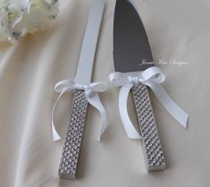 two knifes with bows on them sitting next to each other in front of a flower