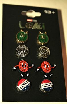 four pin badges are sitting in a black box on a white table and one is red, the other is green