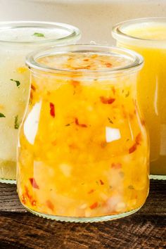 three jars filled with food sitting on top of a wooden table next to each other