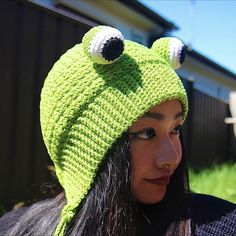 a woman wearing a green knitted hat with two googly eyes