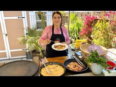 a woman holding a plate of food in front of some pots and pans on a table