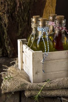 three bottles of olive oil in a wooden crate with twine of twine on top