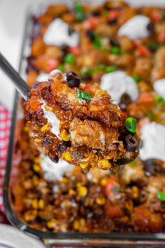 a close up of a spoon full of food with sour cream and toppings on it