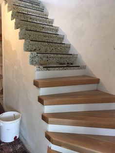 there is a bucket sitting on the floor next to some stairs that have been painted white