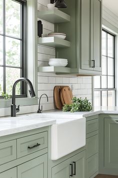 a kitchen with green cabinets and white subway backsplash, black faucet