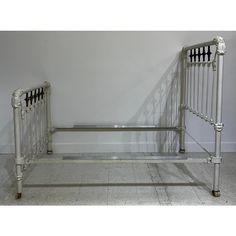 a metal bed frame sitting on top of a tiled floor next to a white wall