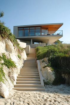 stairs lead up to the top of a house on a cliff overlooking the beach and ocean